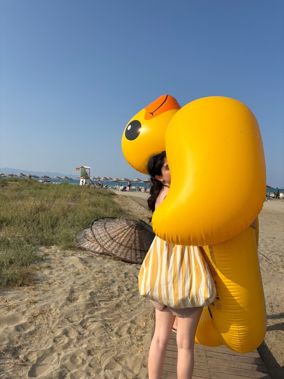 Mia carrying a giant inflatable duck at the beach